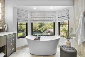 Full bathroom featuring a soaking tub, vanity, tile patterned floors, and baseboards