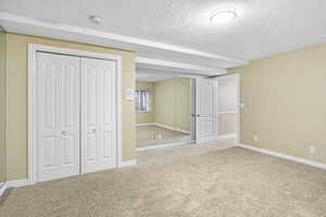 Unfurnished bedroom featuring carpet floors, baseboards, and a textured ceiling