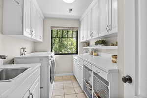 Laundry room with cabinet space, washer and dryer, baseboards, and light tile patterned flooring