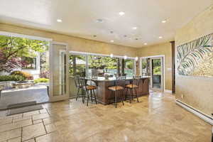 Indoor wet bar featuring french doors, healthy amount of natural light, recessed lighting, and stone tile floors