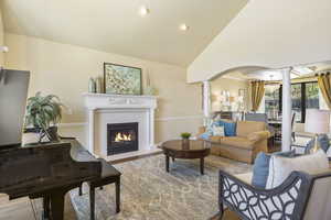 Living room featuring decorative columns, arched walkways, wood finished floors, recessed lighting, and lofted ceiling