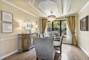 Dining room featuring a chandelier, light wood finished floors, baseboards, and ornamental molding