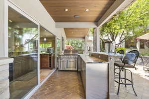View of patio featuring exterior kitchen and a grill