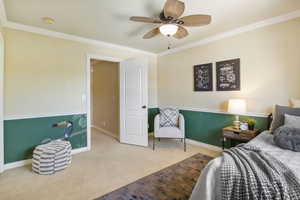 Carpeted bedroom with crown molding, baseboards, and ceiling fan