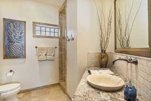 Bathroom with toilet, a walk in shower, tasteful backsplash, vanity, and baseboards