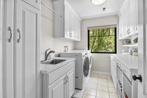 Washroom with cabinet space, separate washer and dryer, baseboards, and light tile patterned flooring