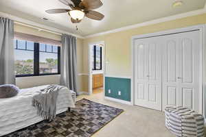 Bedroom with light colored carpet, crown molding, a closet, baseboards, and ensuite bath
