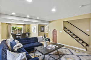 Carpeted living room featuring baseboards, stairs, and recessed lighting