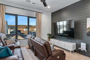 Living area with wooden walls, carpet flooring, ceiling fan, and recessed lighting
