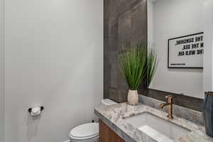 Bathroom featuring toilet, vanity, and baseboards