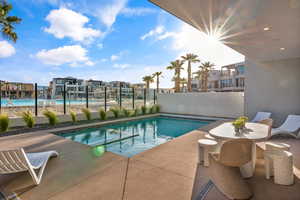 View of swimming pool featuring a pool with connected hot tub, fence, and a patio area