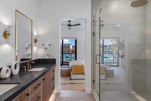 Ensuite bathroom featuring a stall shower, tile patterned floors, double vanity, and a ceiling fan