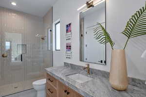Bathroom with a tile shower, toilet, vanity, and recessed lighting