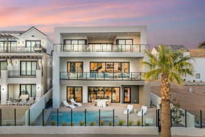 Back of property featuring a balcony, stucco siding, a fenced backyard, an outdoor pool, and a patio area