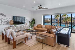 Living area featuring light wood-style flooring, a ceiling fan, and recessed lighting
