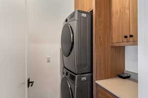 Laundry room featuring cabinet space and stacked washer / dryer