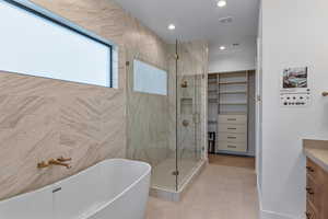 Full bathroom with a stall shower, a freestanding tub, vanity, tile patterned floors, and recessed lighting