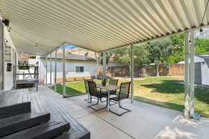 View of patio / terrace with an outdoor structure, outdoor dining area, a deck, and a shed