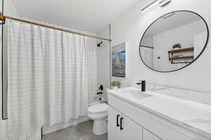 Bathroom featuring shower / bath combination with curtain, vanity, toilet, and tile patterned floors