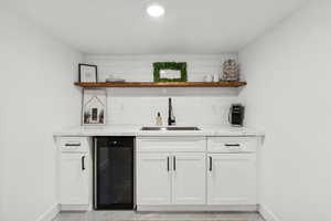 Indoor wet bar with beverage cooler, baseboards, and tasteful backsplash
