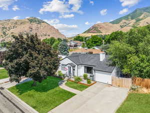 View of front of home featuring a mountain view, a shingled roof, concrete driveway, a chimney, and an attached garage