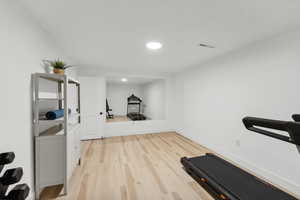 Exercise room with light wood-style floors, recessed lighting, and baseboards