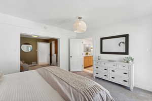 Bedroom featuring light carpet, baseboards, and connected bathroom