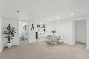 Dining space with wet bar, light carpet, recessed lighting, and baseboards