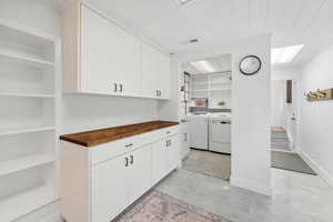 Kitchen featuring washing machine and dryer, wood counters, white cabinets, and built in features