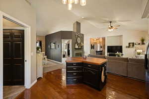 Kitchen featuring butcher block counters, a fireplace, dark cabinets, a ceiling fan, and lofted ceiling