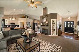 Living room featuring lofted ceiling, a ceiling fan, dark colored carpet, built in shelves, and baseboards