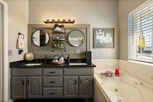 Full bath with healthy amount of natural light, double vanity, and a whirlpool tub