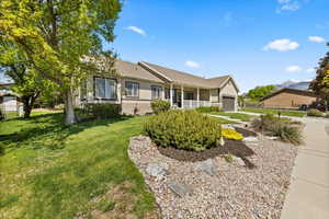 Ranch-style home featuring an attached garage, a front yard, brick siding, and covered porch