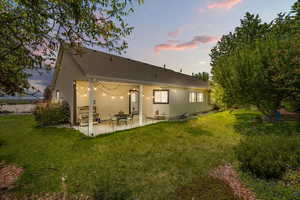 Back of house featuring a patio, a yard, and stucco siding