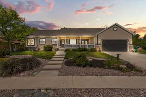 Single story home with covered porch, an attached garage, concrete driveway, stucco siding, and a lawn