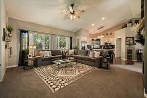 Living area with vaulted ceiling, ceiling fan, dark carpet, baseboards, and a chandelier