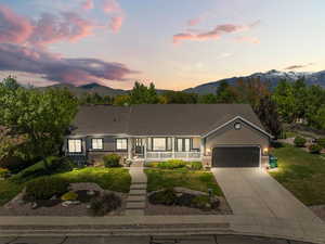 Single story home with covered porch, a mountain view, an attached garage, and a front lawn