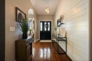Entrance foyer featuring arched walkways, dark wood-style flooring, and baseboards