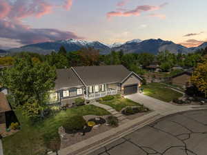 Ranch-style home with a porch, an attached garage, driveway, and a mountain view