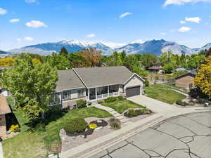 Ranch-style house featuring covered porch, an attached garage, driveway, a front lawn, and a mountain view
