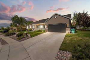 Ranch-style house with an attached garage, a lawn, driveway, a porch, and brick siding