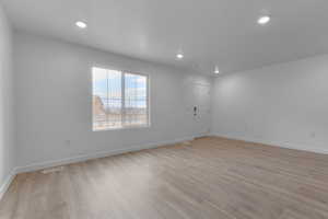 Empty room featuring light wood-style floors, baseboards, and recessed lighting