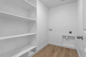 Clothes washing area featuring electric dryer hookup, washer hookup, light wood-style floors, and baseboards
