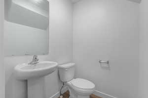 Bathroom featuring wood finished floors, toilet, baseboards, and a sink