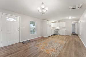 Interior space with laminate flooring, an inviting chandelier, and lofted ceiling