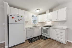 Beautiful kitchen featuring white cabinetry, under cabinet range hood and laminate flooring.