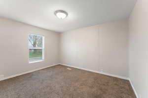 Carpeted empty room featuring a textured ceiling and baseboards