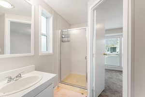 Ensuite primary bathroom featuring stand up shower, vanity and laminate flooring