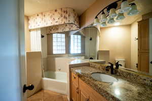 Bathroom featuring a garden tub, tile patterned flooring, a textured ceiling, toilet, and vanity