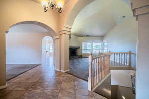 Hall with carpet, arched walkways, baseboards, lofted ceiling, and a chandelier
